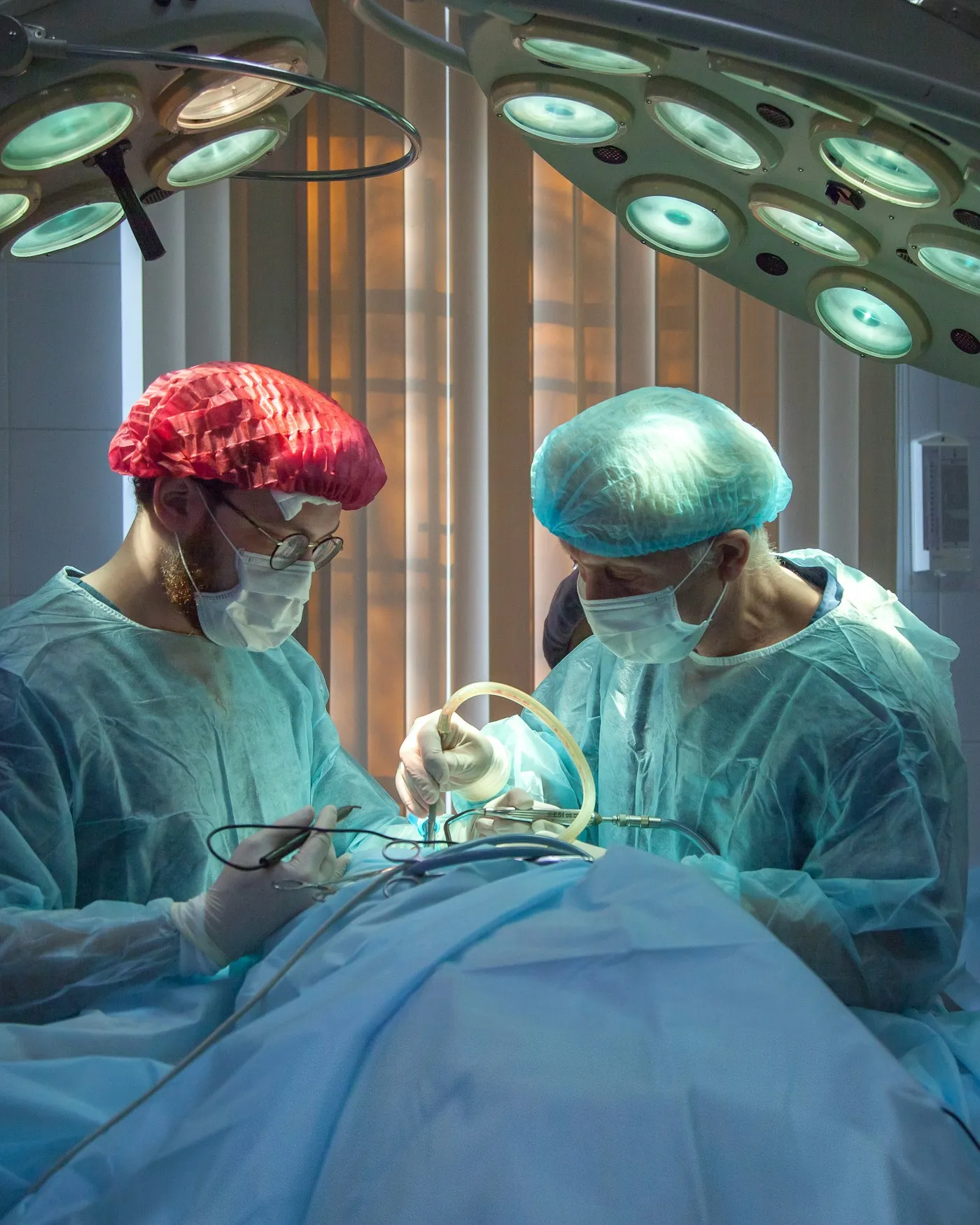 Two surgeons operating under bright theatre lights